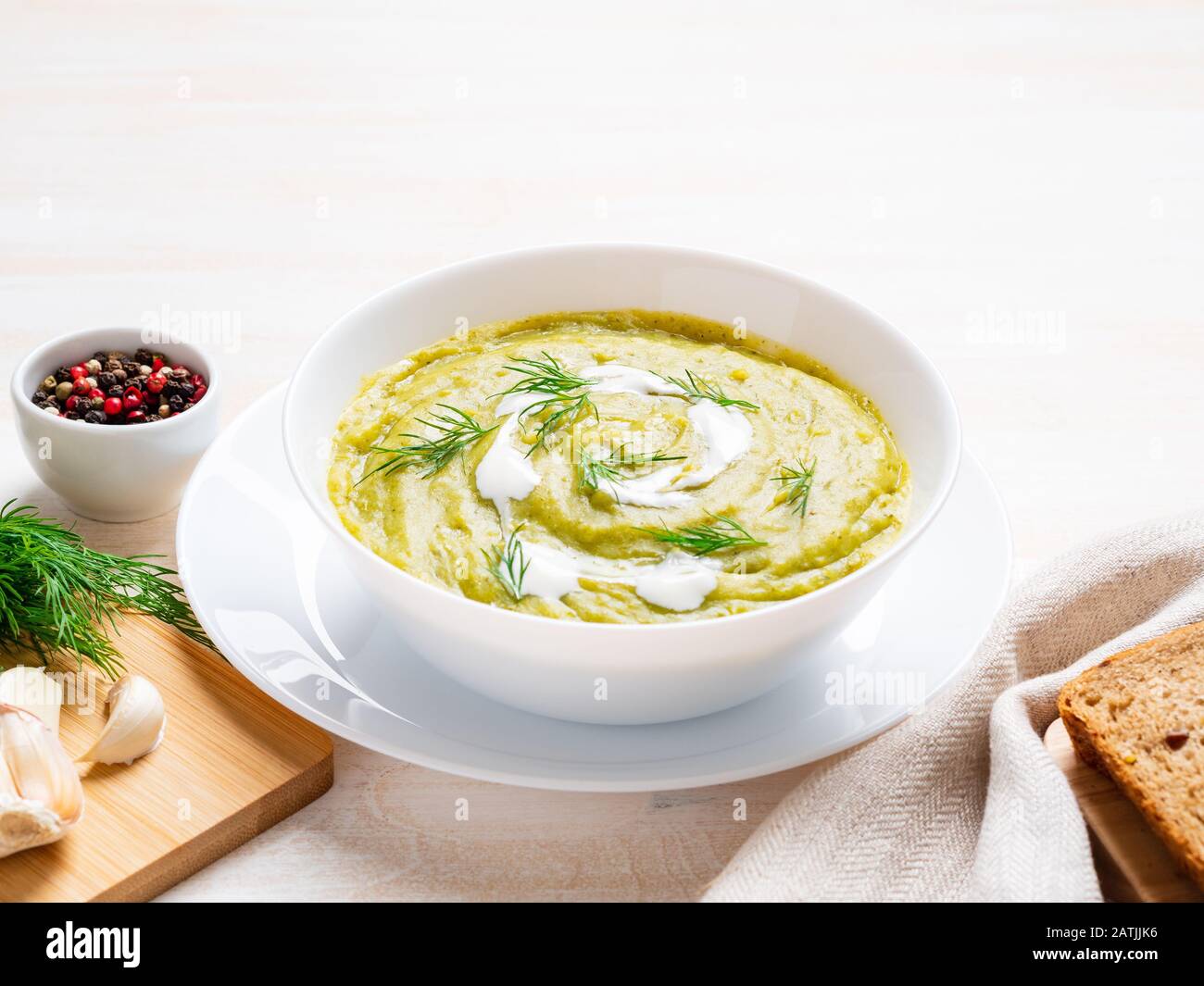 Große weiße Schüssel mit pflanzlich grüner Cremetuppe aus Brokkoli, Zucchini, grünen Erbsen auf weißem Hintergrund, Seitenansicht Stockfoto