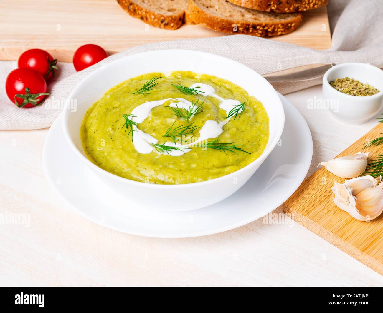 Große weiße Schüssel mit pflanzlich grüner Cremetuppe aus Brokkoli, Zucchini, grünen Erbsen auf weißem Hintergrund, Seitenansicht Stockfoto