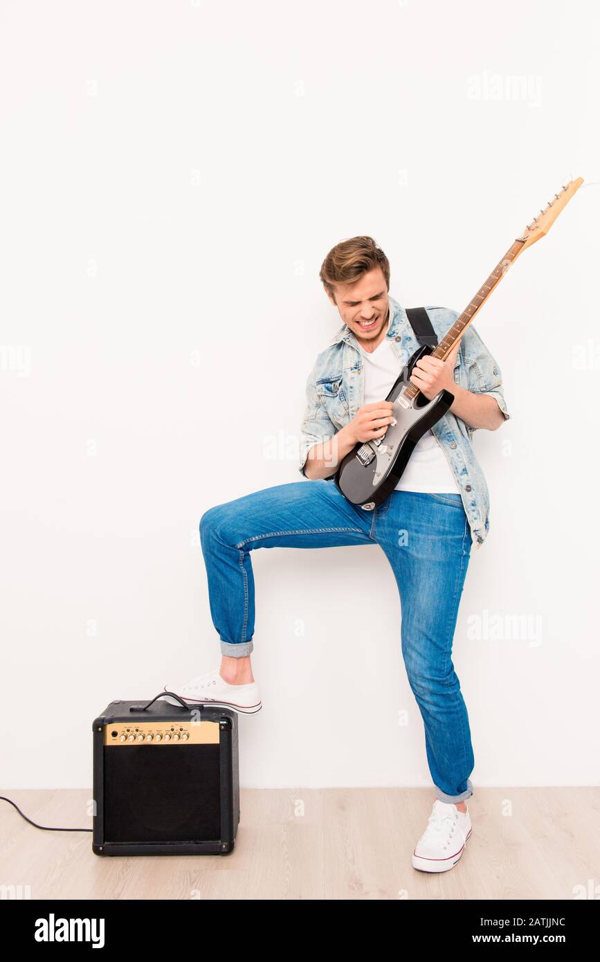 Junge fröhliche coole Rocker, die auf E-Gitarre spielen Stockfoto