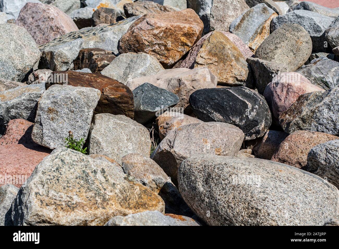 Blöcke verschiedener Arten von Steinen, die das Erstarken des Meeresufers als Hintergrund bilden Stockfoto