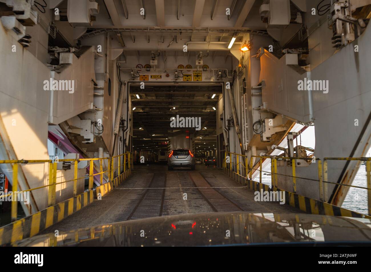 Die Bugtüren sind offen und Autos fahren abends in einem großen Autofähren Autodeck im Hafen von Turku Finnland Stockfoto