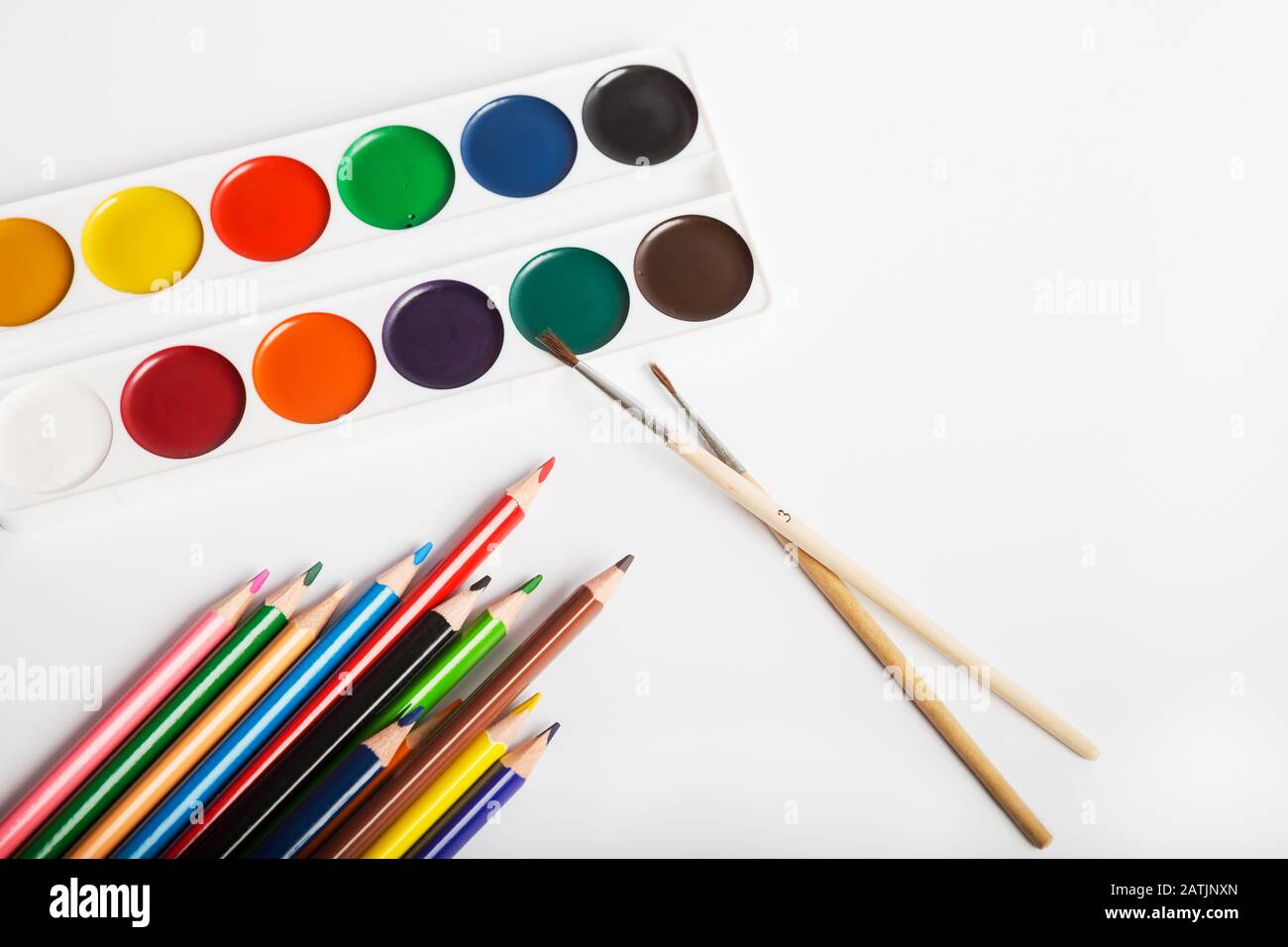 Set mit Aquarellfarben mit Pinsel und Farbstiften zum Zeichnen auf weißem Hintergrund Stockfoto