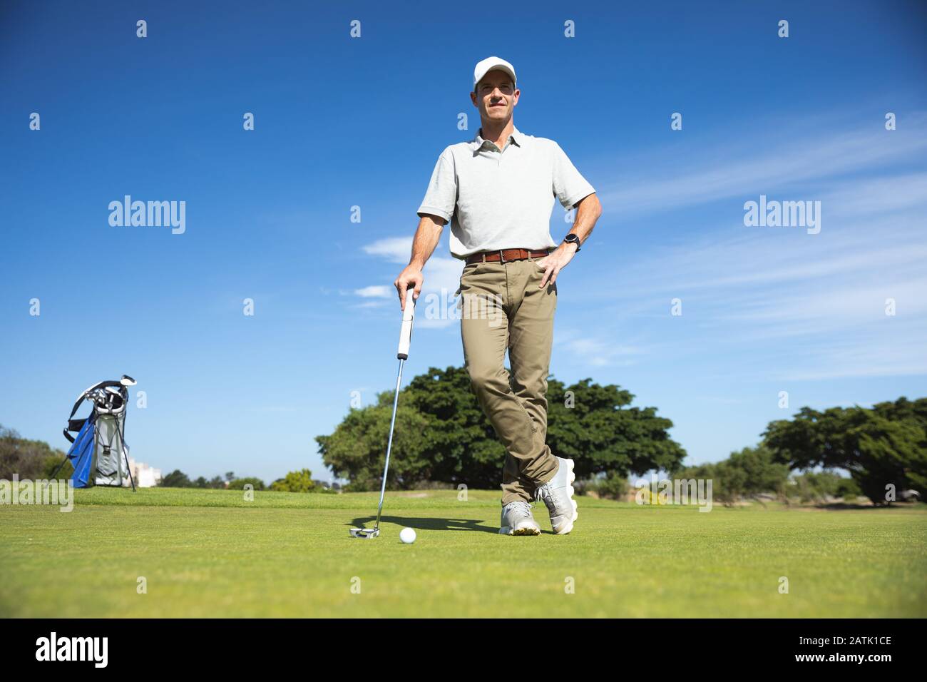 Golfer, der die Kamera betrachtet und einen Golfclub hält Stockfoto