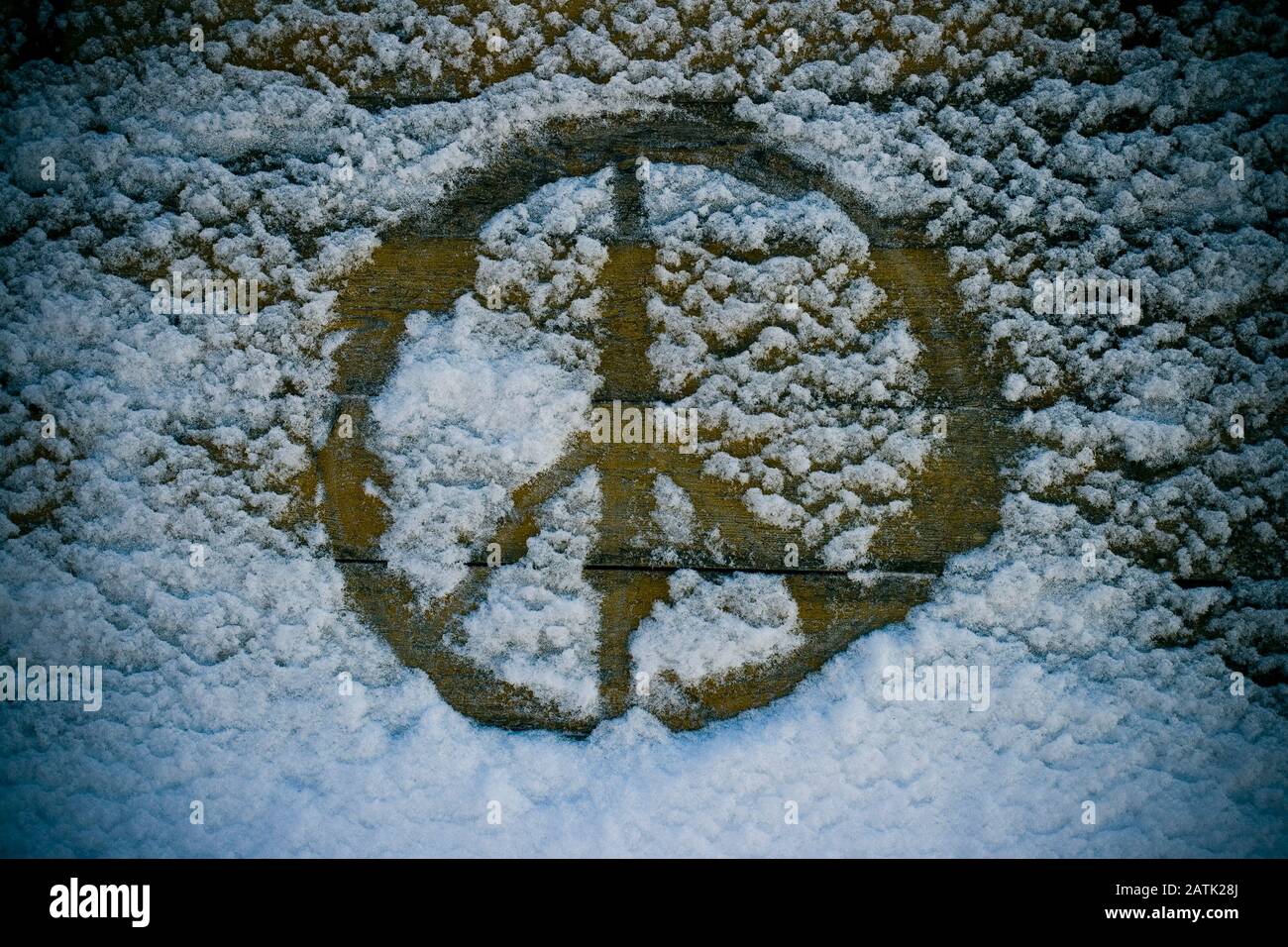 Ein Friedenszeichen, das auf einem alten Holzbrett in den Schnee eindringen kann Stockfoto