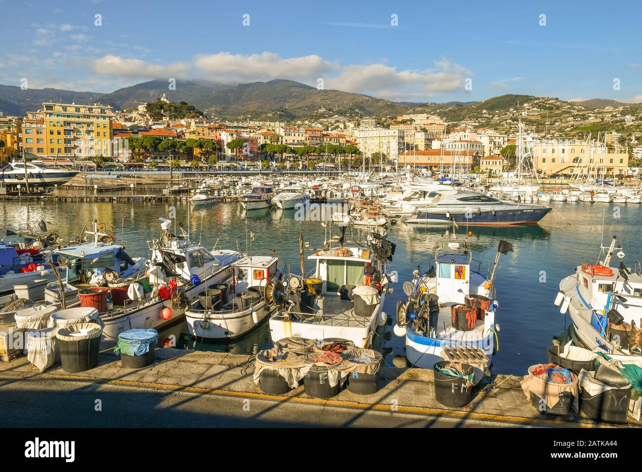 Malerische Aussicht auf den Hafen mit Fischerbooten und Luxusyachten, die an den Piers und der Küstenstadt im Hintergrund angedockt sind, Sanremo, Ligurien, Italien Stockfoto
