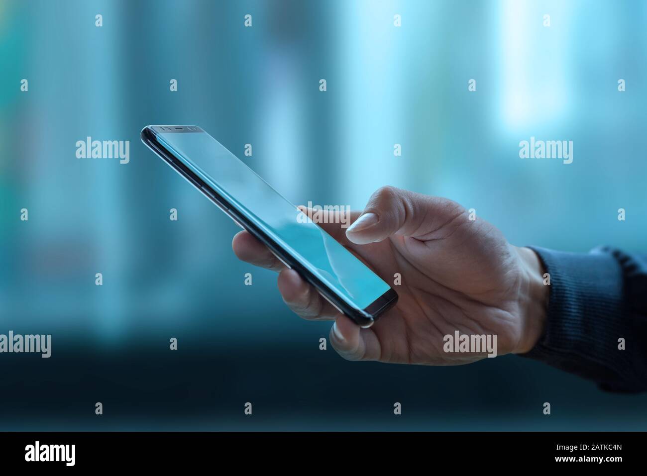 Telefon in Mannhand. Blaue Fenster, Business Center im Hintergrund. Konzept der globalen Nutzung mobiler Technologien Stockfoto
