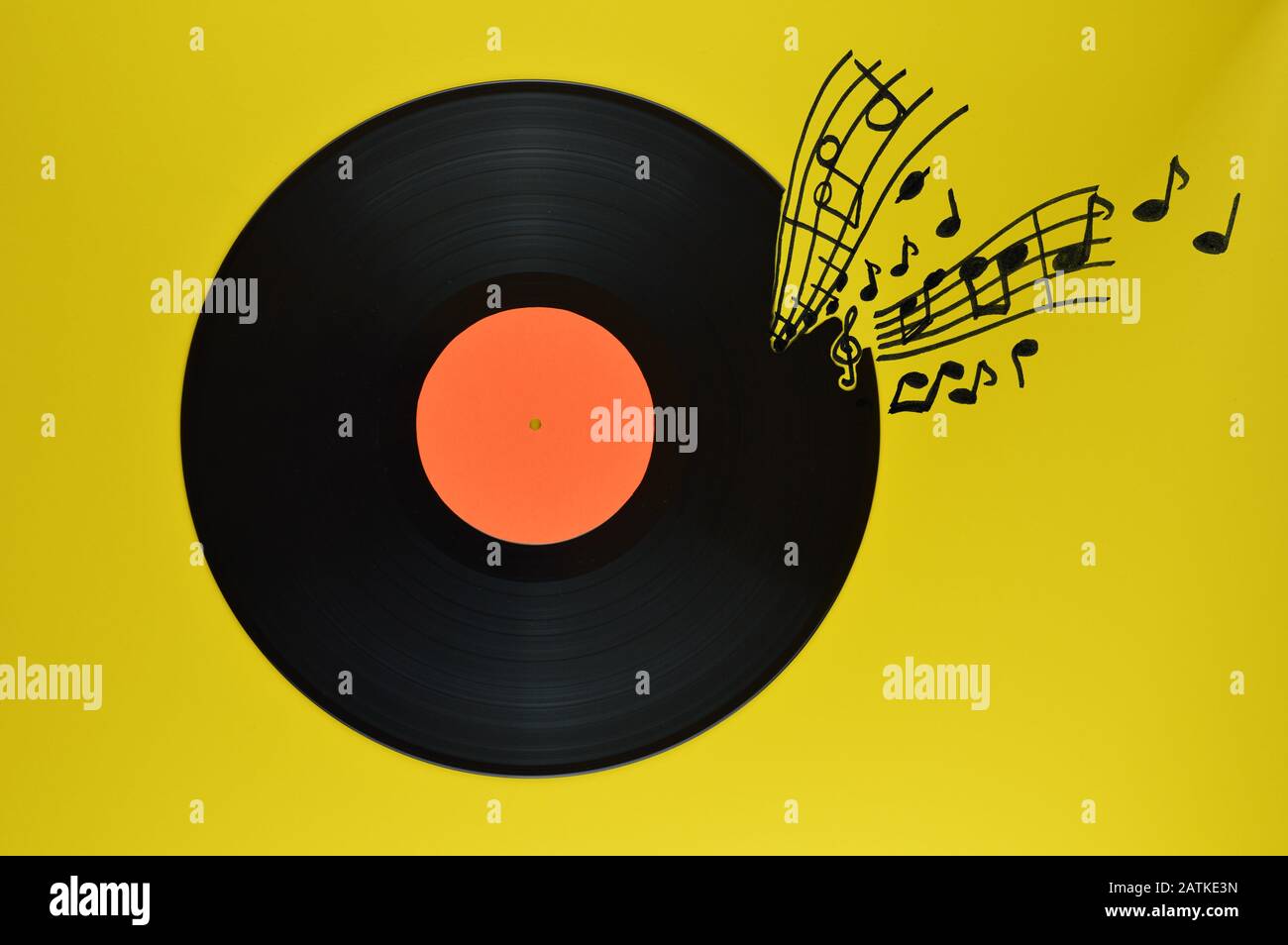 Alte schwarze Schallplatte mit leerem orangefarbenem Etikett, das auf gelbem Hintergrund mit Noten und Stangen zentriert ist Stockfoto