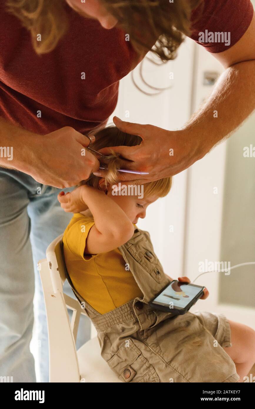 Papa schneidet Haare zu kleinen Sohn Stockfoto