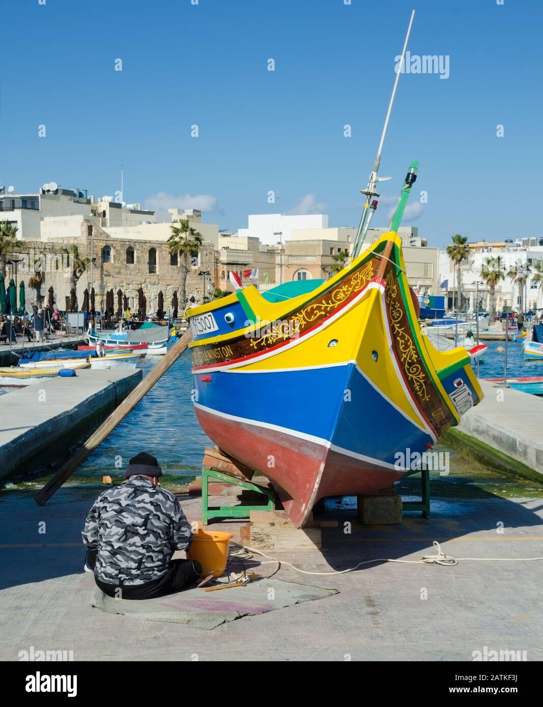 MARSAXLOKK, MALTA. Dezember 2019. Ein Fischer frischt die bemalten Augen Osiris auf dem Reck seines maltesischen "Luzzu" auf - eines der leuchtenden Kol Stockfoto