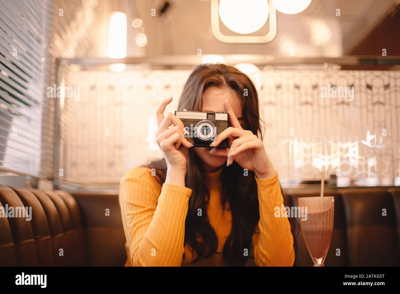 Teenager-Mädchen fotografieren mit Vintage-Kamera während im Café sitzen Stockfoto