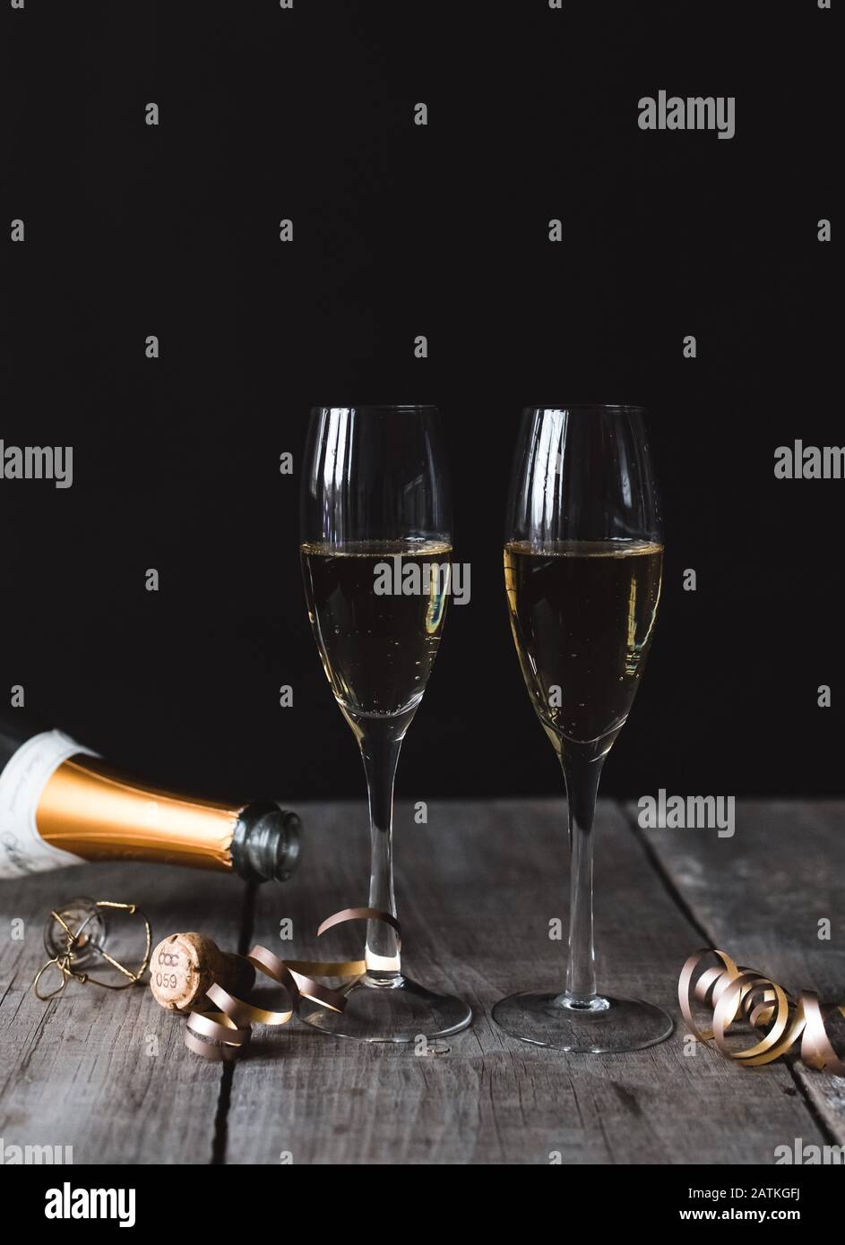 Zwei Gläser Champagner und Flaschenoberteil mit schwarzem Hintergrund. Stockfoto