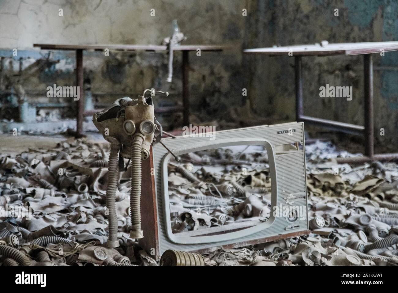 Gasmasken auf dem Boden mit einem alten Fernseher in einer verlassenen Mittelschule in Pripyat - Atomkraftwerkzone von Tschernobyl der Entfremdung Stockfoto