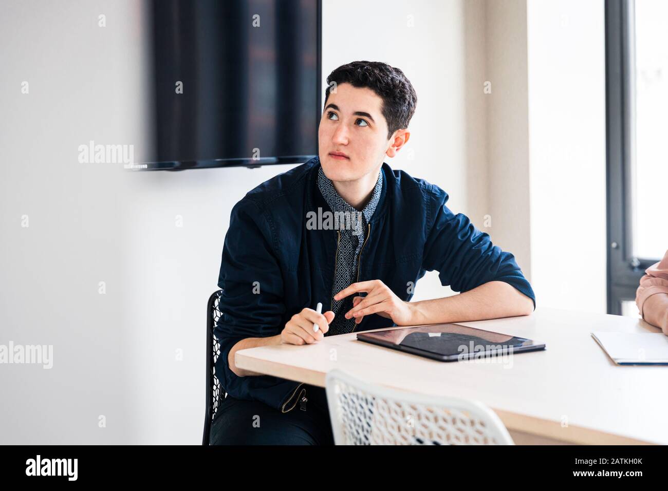 Junger Geschäftsmann, der sich während des Treffens im Büro am Tisch konzentriert Stockfoto