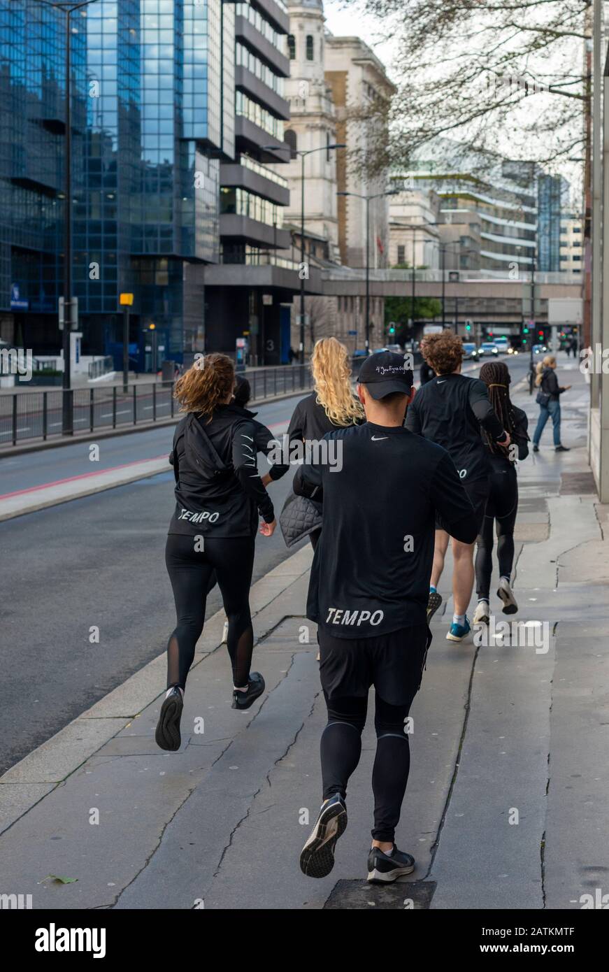 Gemischte Gruppe von Läufern am Sonntagmorgen oder Joggern in passenden schwarzen Outfits, die in der Lower Thames Street, London, Großbritannien Laufen oder Joggen üben Stockfoto