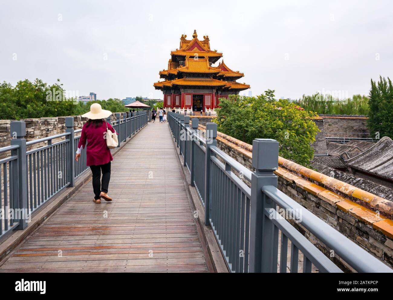 Chinesin trägt Strohhut, die an der Palastmauer mit Eckturm, Verbotene Stadt, Peking, China, Asien spazieren geht Stockfoto
