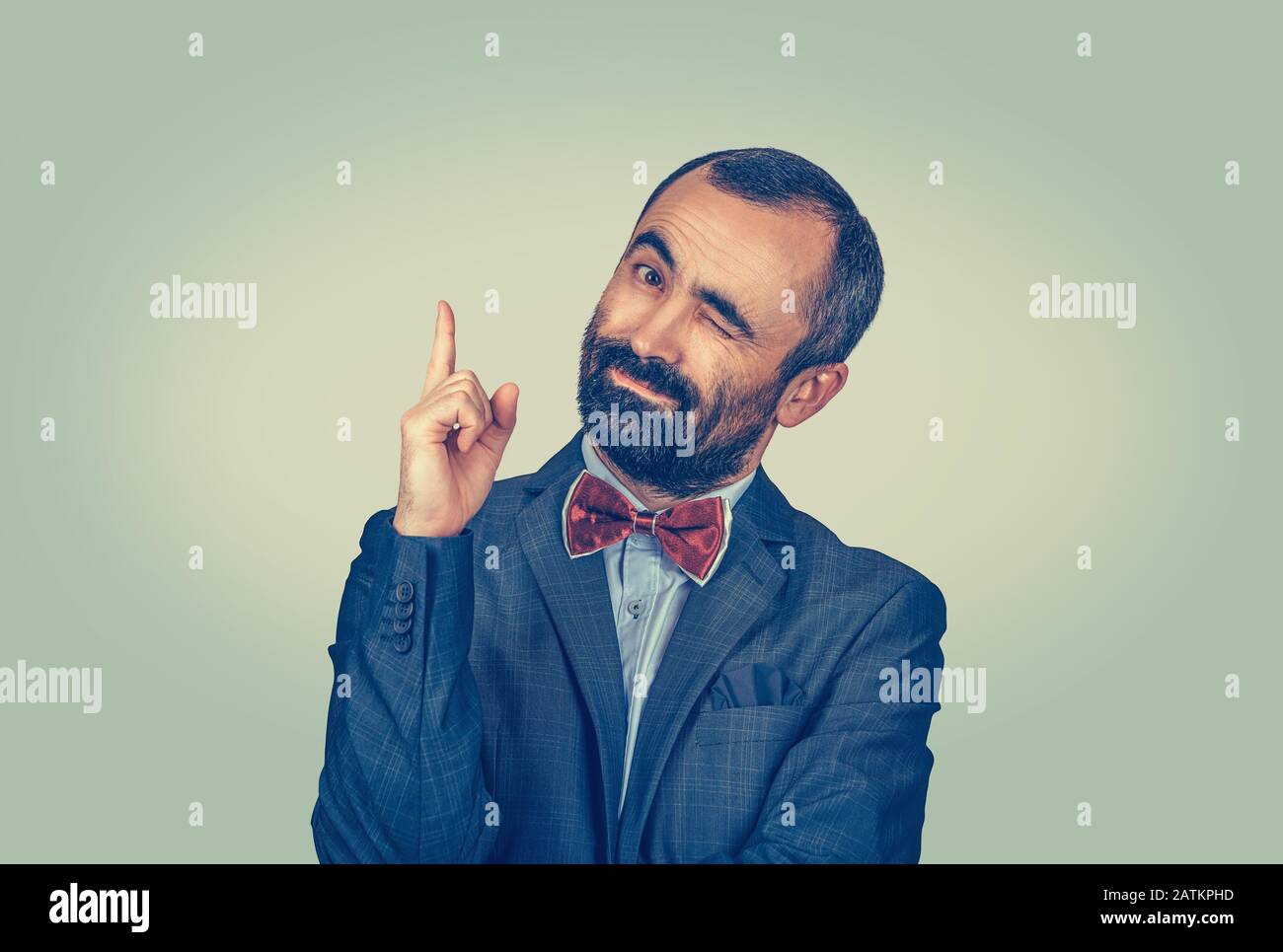 Reifer Geschäftsmann winkelt nach oben und sieht die Kamera fröhlich an. Mixed Race Bärtiermodell isoliert auf grüngelbem Studiohintergrund mit Kopierraum Stockfoto