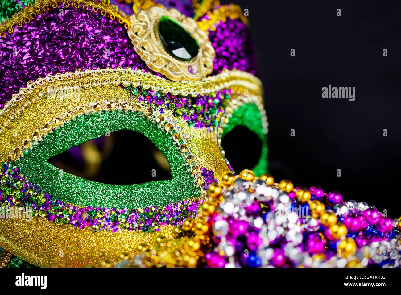 Nahansicht einer Jester-Maske mit farbigen Perlen, die im Vordergrund verschwommen sind. Schwarzer Hintergrund. Stockfoto