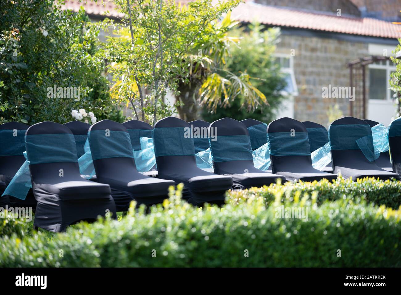 Die Stühle sind für Gäste bei der Hochzeit im Freien in den Sommermonaten mit hellem grünen Gras eingerichtet Stockfoto