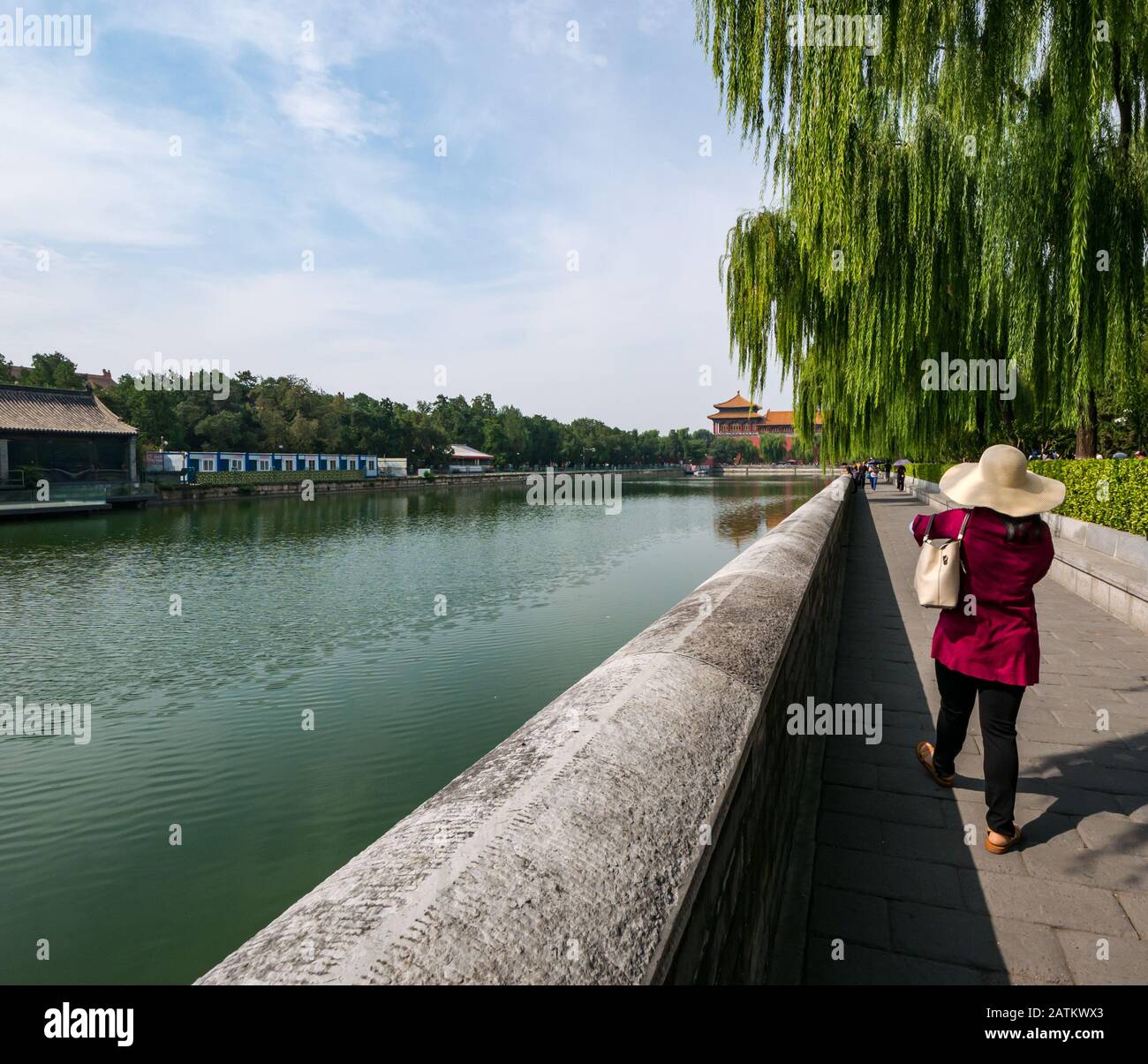 Frau in einem breit umkrempelten Strohhut, die am Schlossgraben, In Der Verbotenen Stadt, in Peking, China und Asien spazieren geht Stockfoto