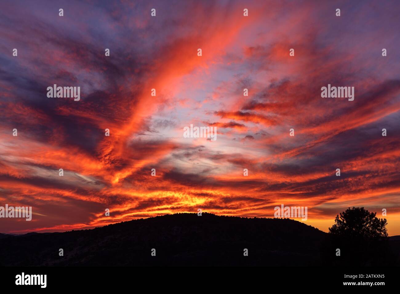 Farbenfroher Himmel mit dramatischen Wolken und Berg-Silhouette im Hintergrund. Stockfoto