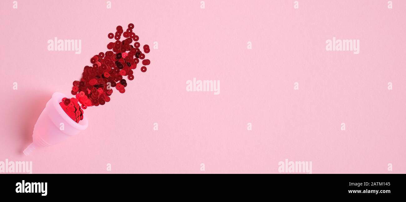 Menstruationsbecher gefüllt mit rotem Konfetti auf pinkfarbenem Hintergrund mit Kopierraum. Banner-Design für Beauty-Blog. Alternative Menstruationshygiene. Kritisch d Stockfoto