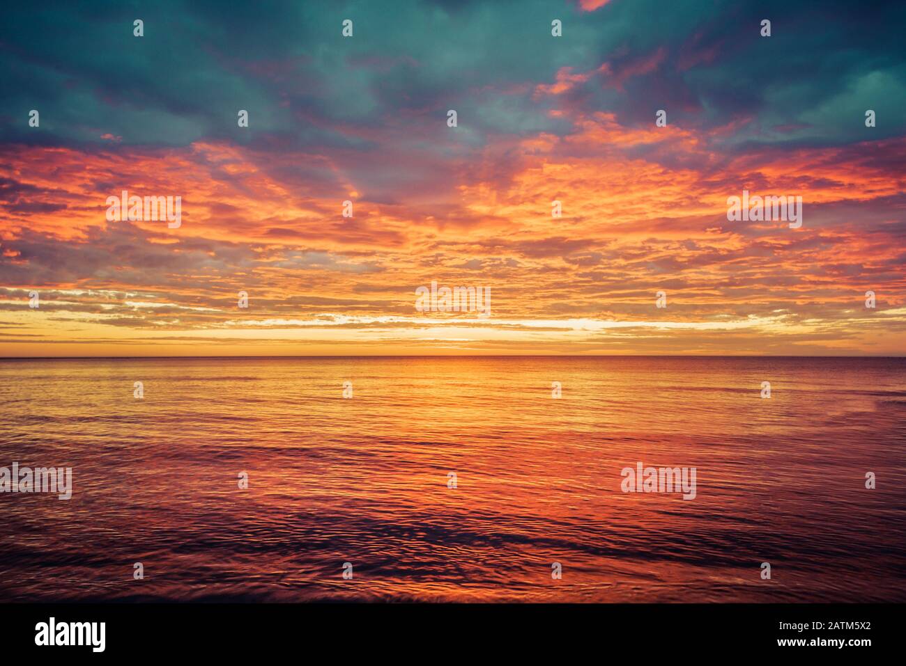 Malerischer Sonnenaufgang über dem Meer. Dramatischer Himmel in Orange und Rot. Stockfoto