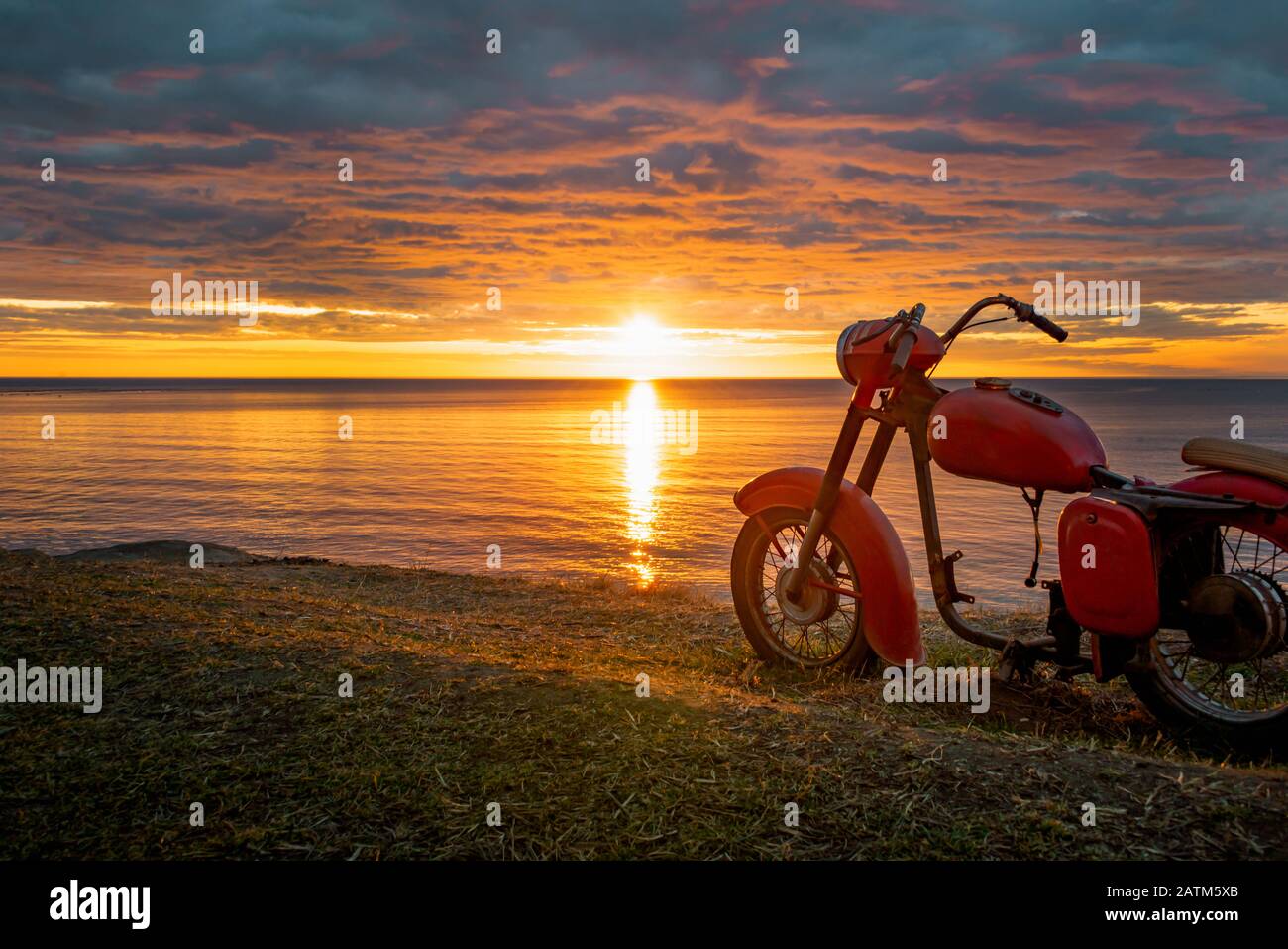 Ein Skelett eines alten roten Motorrads gegen den malerischen Sonnenaufgang. Stockfoto
