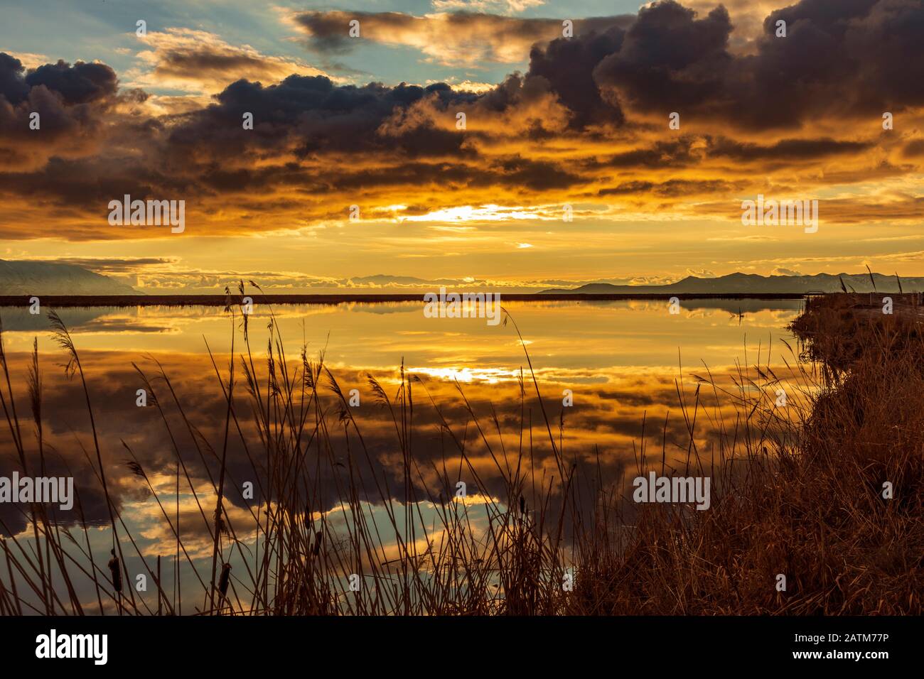 Am späten Nachmittag leuchtet die Sonne auf den Wolken und reflektiert auf dem Wasser in der Farmington Bay Waterfowl Management Area in der Nähe von Farmington, Utah, USA. Stockfoto