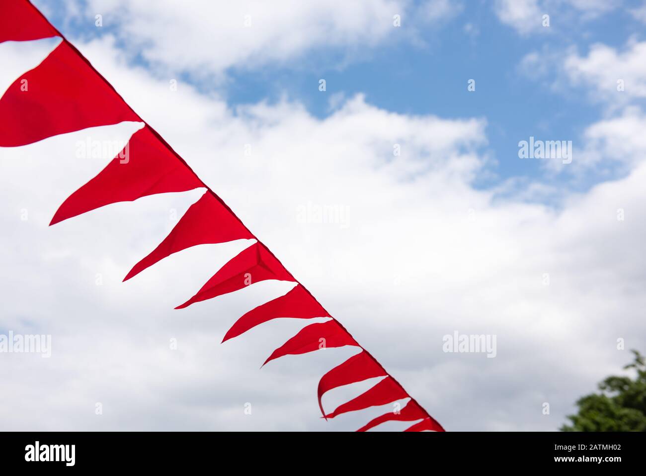 Im Freien hängen rote Textilfahnen zur Dekoration auf. Blu-Sky mit Wolken im Hintergrund. Stockfoto