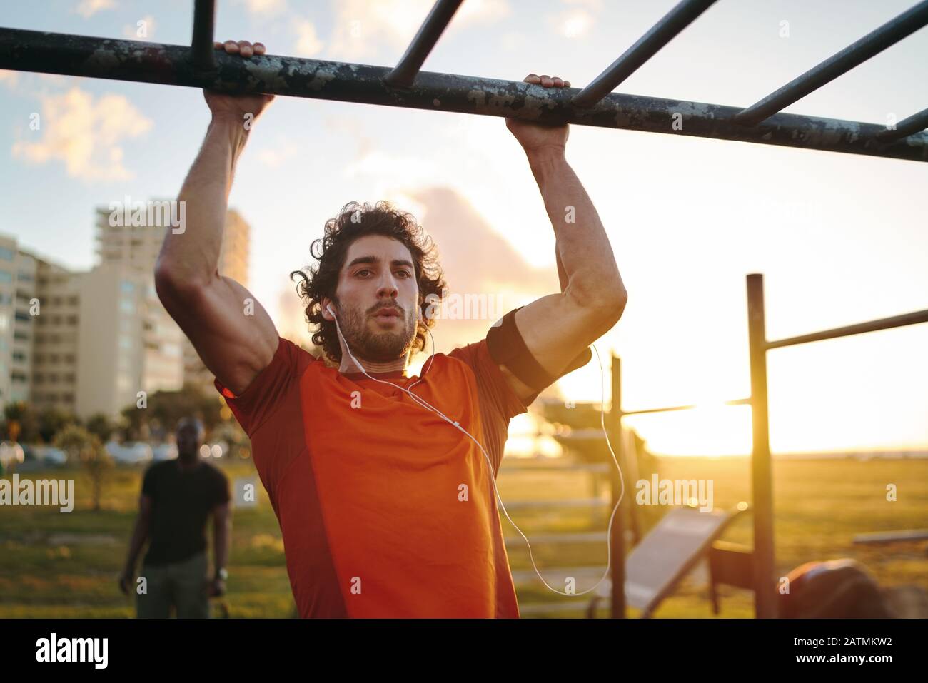 Portrait eines jungen crossfit Sportlers, der an der Bar trainiert und im Sportpark im Freien Pull-ups für Arme und Rückenmuskeln macht Stockfoto