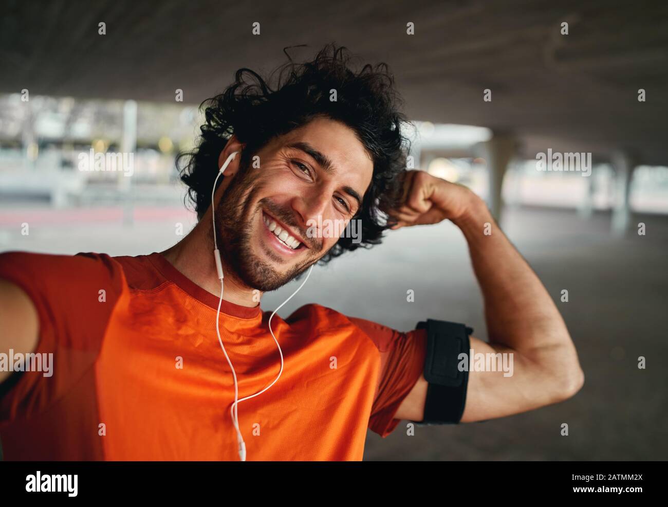 Selbstsicher lächelnder, gutaussehender Sportler, der beim Blick in die Kamera eine selfie und Muskeln beugt Stockfoto