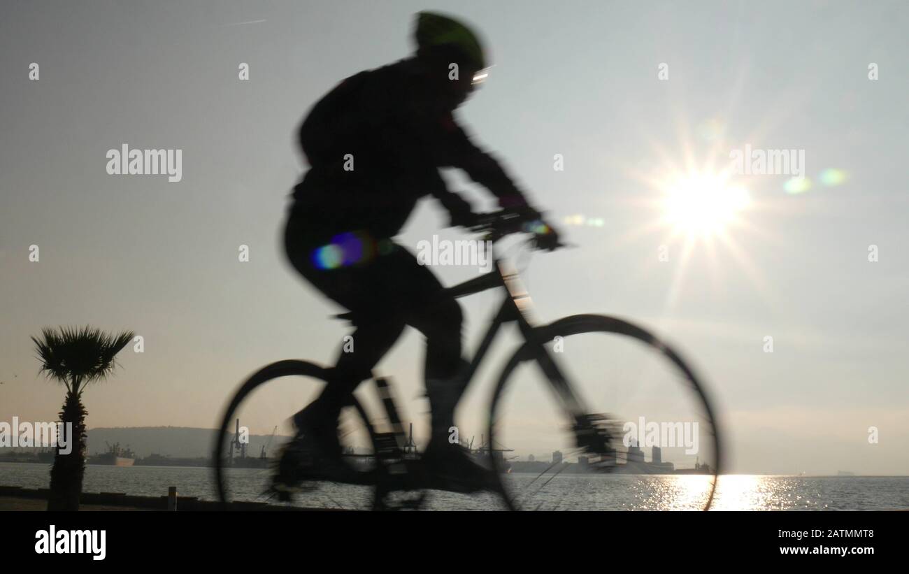 Silhouette des jungen Mannes, der mit dem Vintage-Fahrrad unterwegs ist, mit wunderschönem Himmel bei Sonnenuntergang im Hintergrund. Gesunder aktiver Lebensstil. Izmir, Türkei Stockfoto
