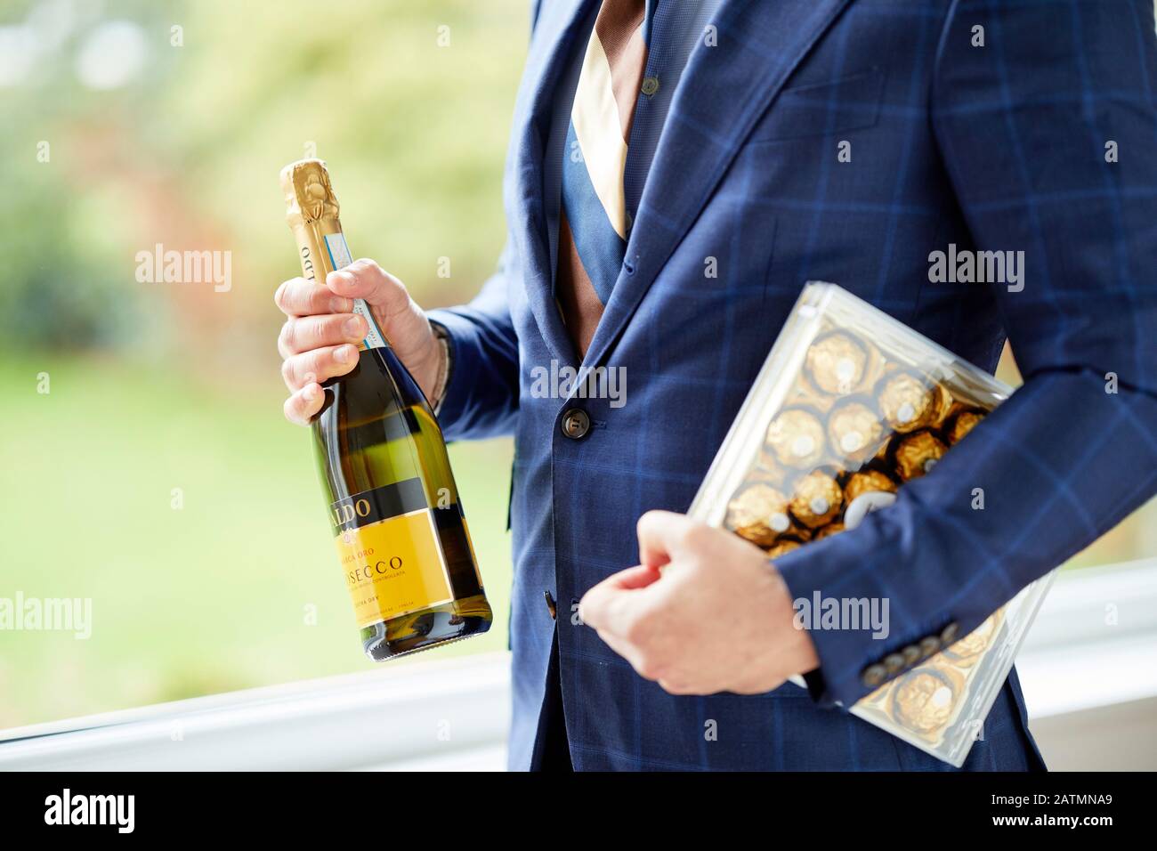 Mann mit Schachtel Pralinen und einer Flasche Wein Stockfoto