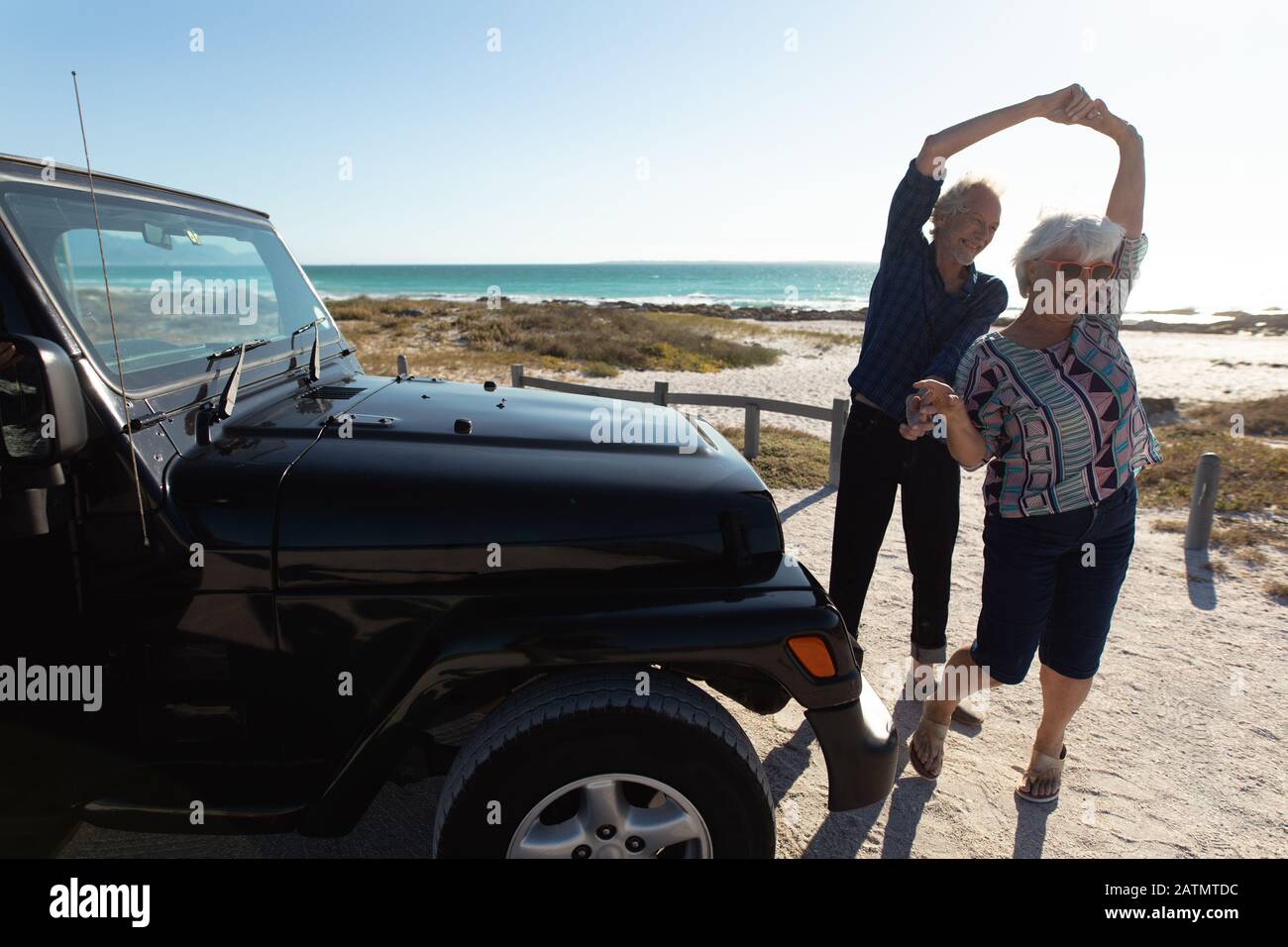 Altes Paar mit Auto am Strand Stockfoto