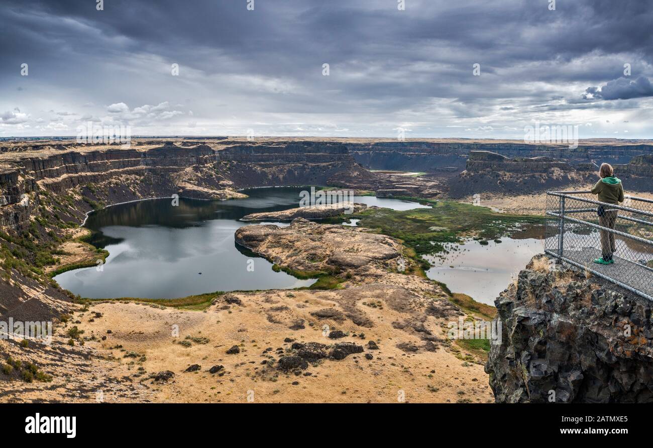 Junge Frau, die Dry Falls Cliffs, Grand Coulee Formation, Channeled Scablands, in der Nähe von Coulee City, Sun Lakes-Dry Falls State Park, Washington USA, betrachtet Stockfoto