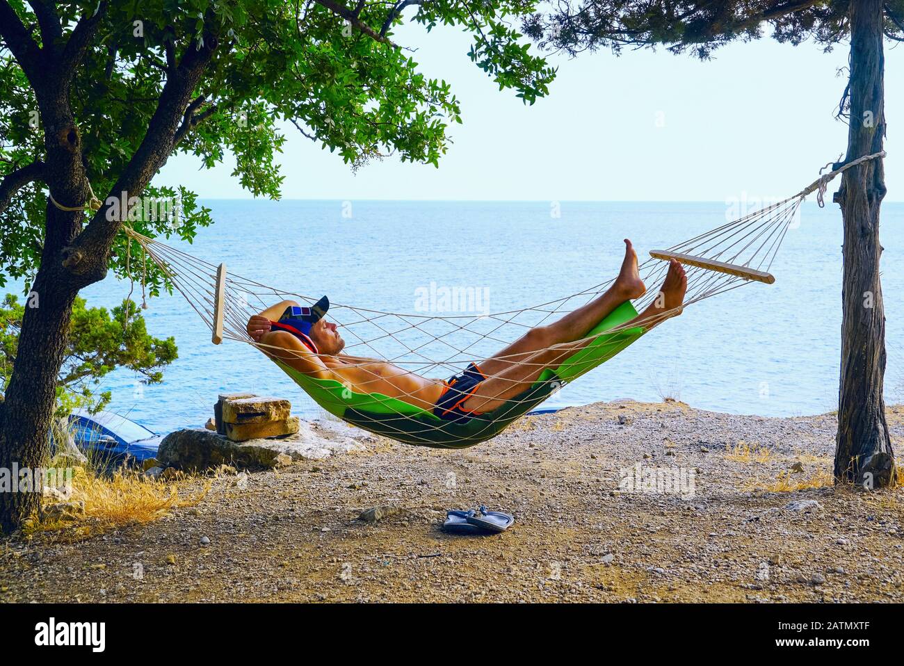 Ein junger Mann ruht in einer Hängematte am Strand Stockfoto