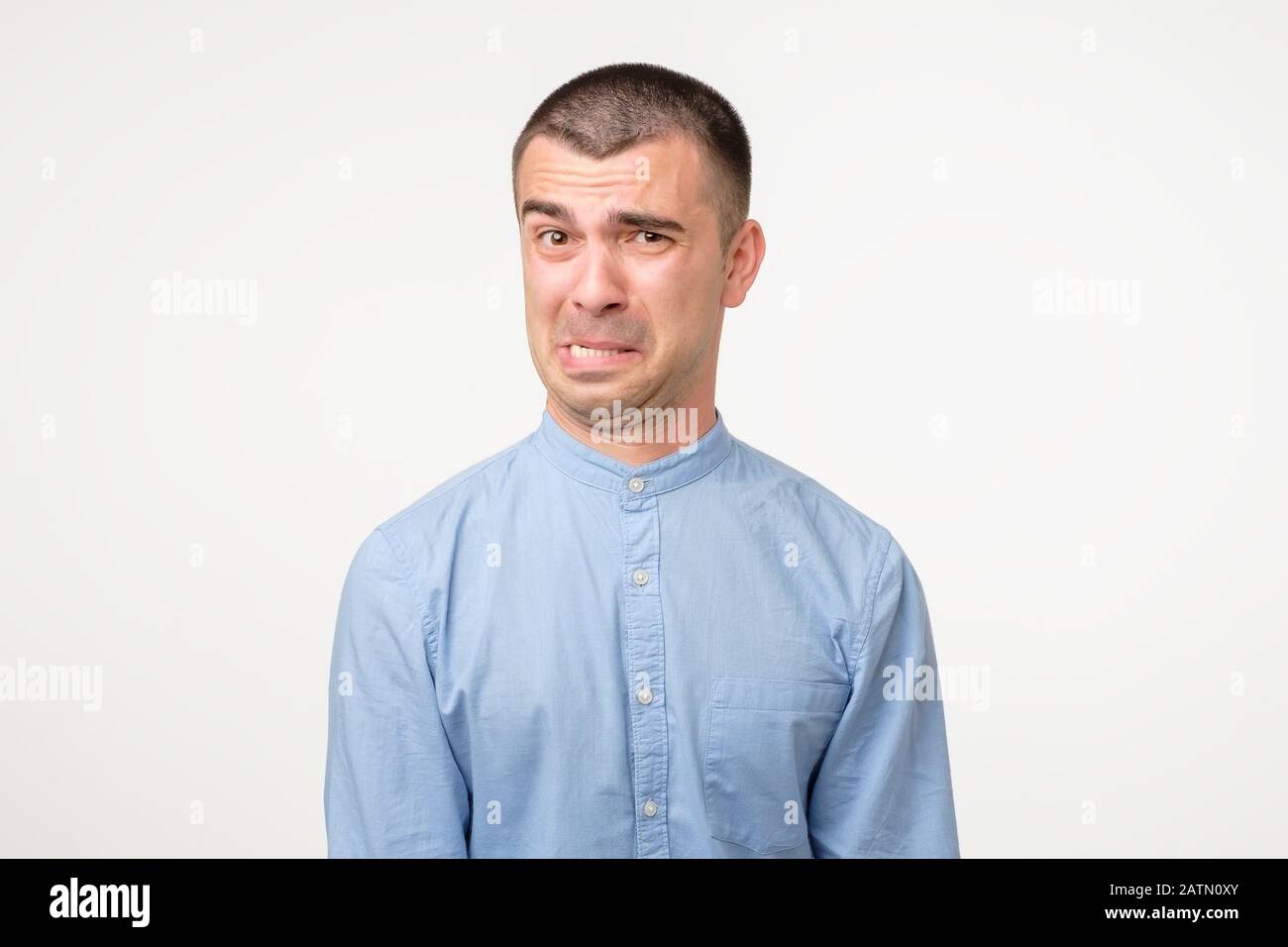 Lustiger junger hispanischer Mann, der zynisch unglücklich wütende Gesichtsausdruck zeigt. Studio gedreht Stockfoto