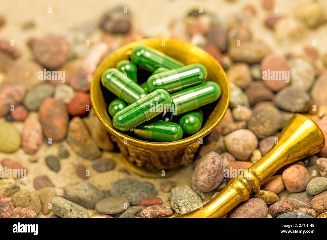 Spirulina-Kapseln in einem Mörtel an einem Strand mit Kieselsteinen Stockfoto