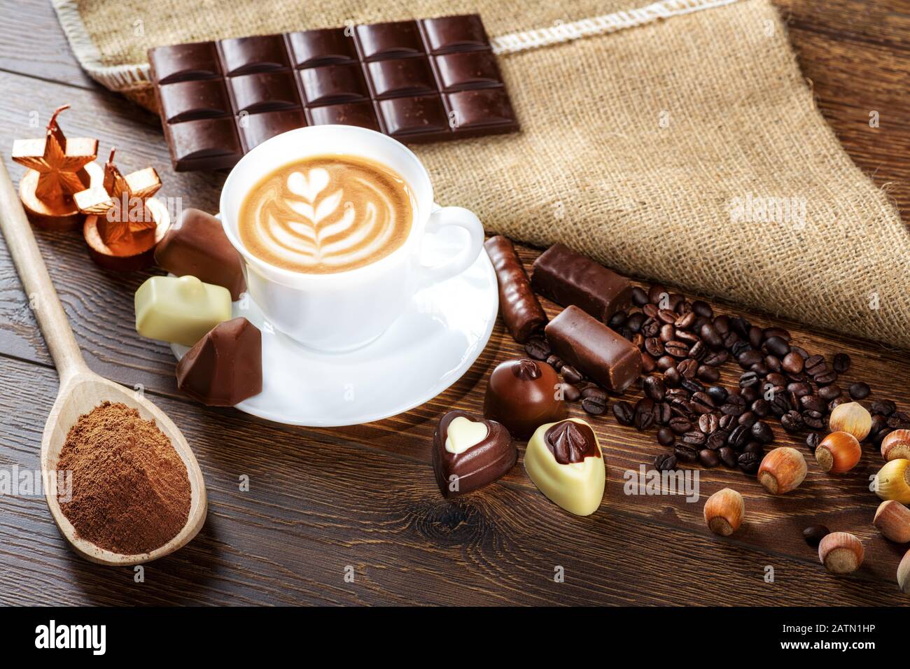 Tasse köstlichen Latte mit Schokolade und gerösteten Kaffeebohnen in Burlap Stockfoto