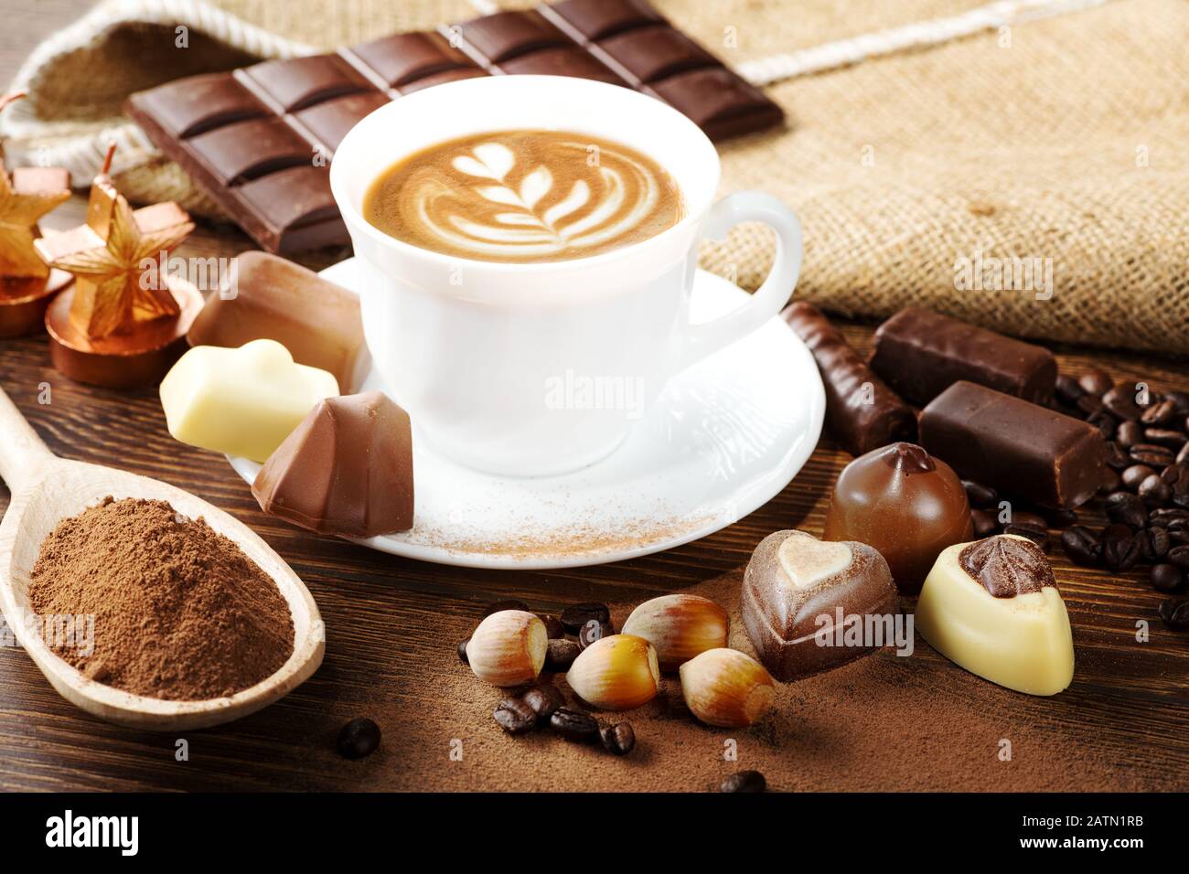 Tasse köstlichen Latte mit Schokolade und gerösteten Kaffeebohnen in Burlap Stockfoto