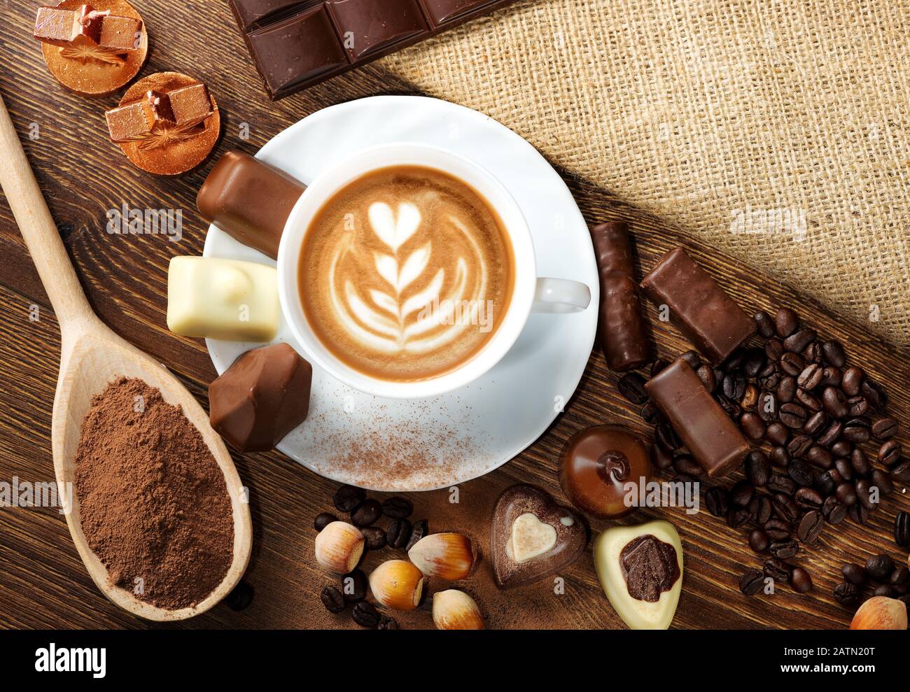 Tasse köstlichen Latte mit Schokolade und gerösteten Kaffeebohnen in Burlap Stockfoto