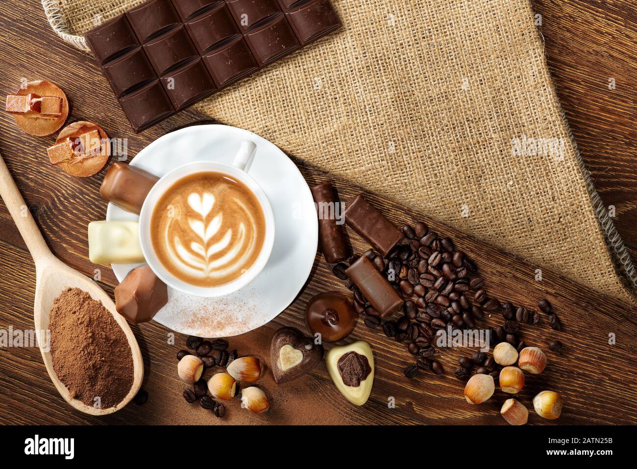Tasse köstlichen Latte mit Schokolade und gerösteten Kaffeebohnen in Burlap Stockfoto