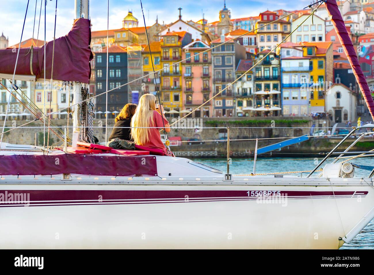 Frauen auf einer privaten Yacht, die Wein trinkt und den Sonnenuntergang in Porto, Portugal genießt. Rückblick. Panorama Altstadt Porto am Fluss Duoro. Oporto Panorama Stockfoto