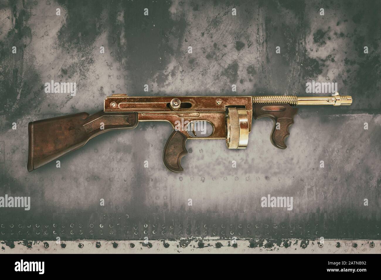 Alte goldfarbene Maschinenpistole vor einem alten verwitterten Betonhintergrund Stockfoto