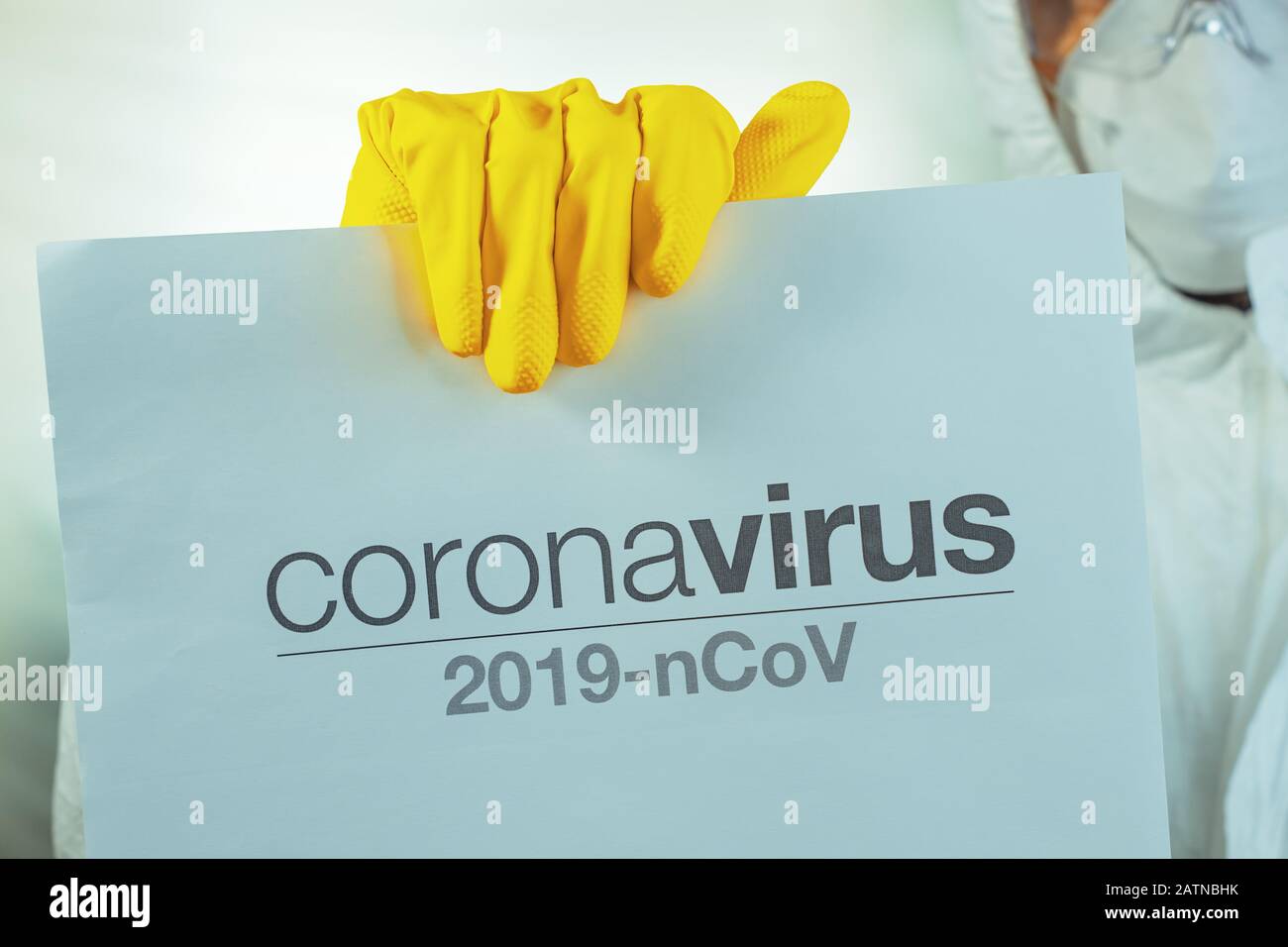 Coronavirus Warnpapier Banner, das von männlichen Epidemiologen in Schutzkleidung gehalten wird Stockfoto