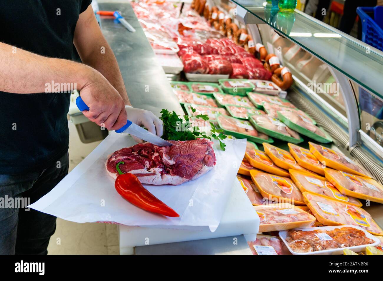 Metzger arbeitet in einer Fleischabteilung eines Marktes und hackt Fleisch. Essen und kulinarisches Konzept Stockfoto