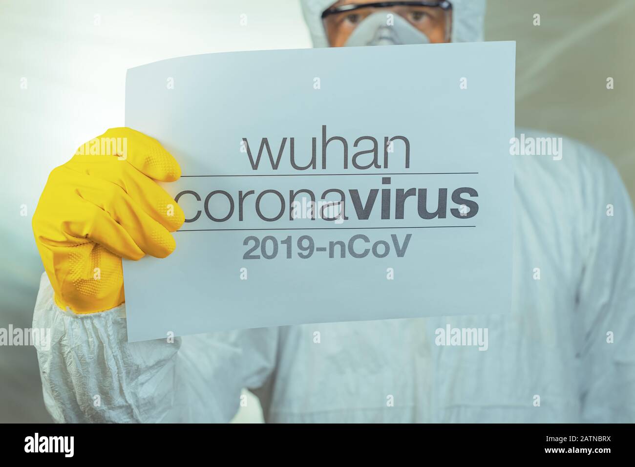 Wuhan Coronavirus Warnpapier Banner, das von männlichen Epidemiologen in Schutzkleidung gehalten wird Stockfoto