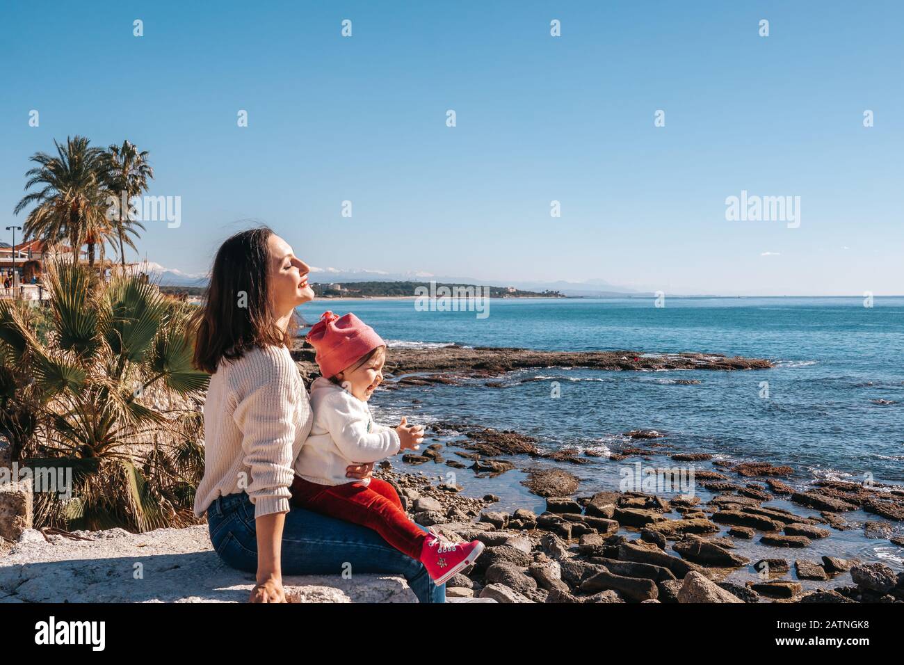 Porträt der glücklichen liebenden Mutter und ihres Babys in schöner Küstenlinie Stockfoto