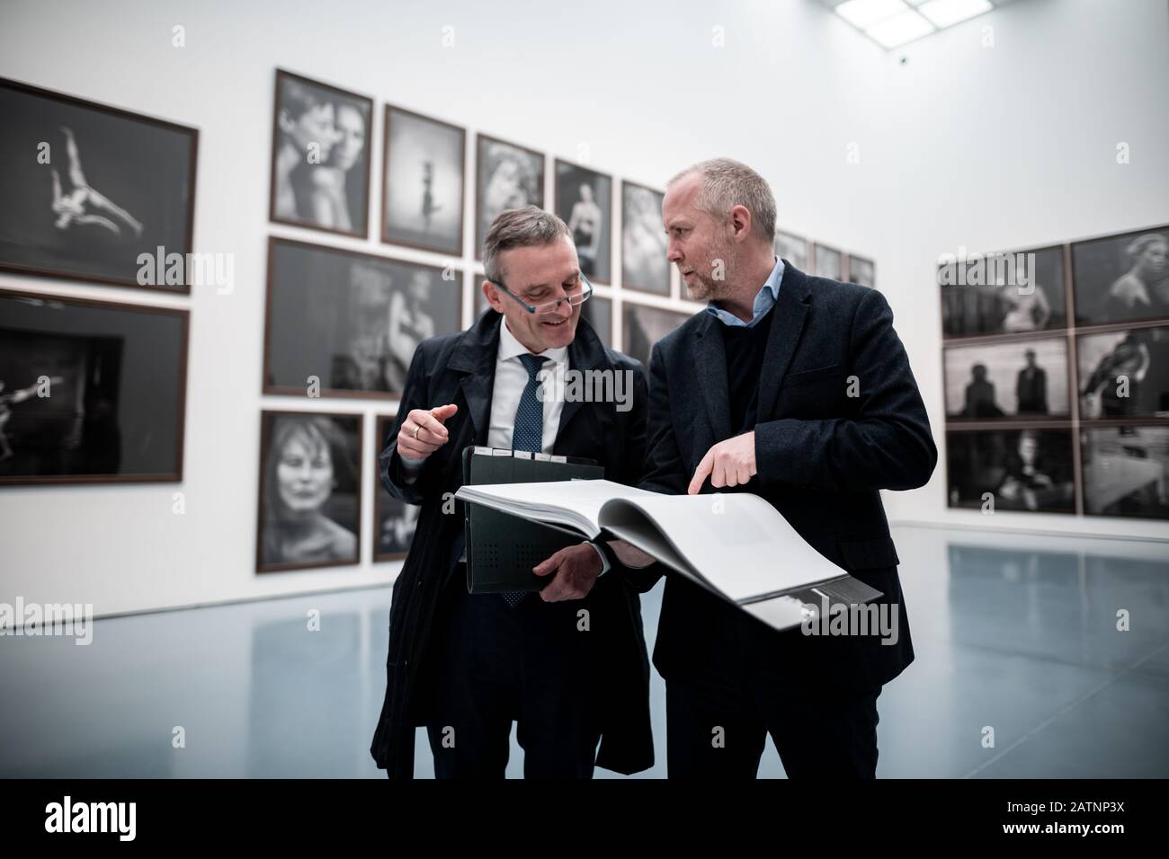 04. Februar 2020, Nordrhein-Westfalen, Düsseldorf: Thomas Geisel, Oberbürgermeister von Düsseldorf und Felix Krämer, Generaldirektor des Kunsthauses (l-r-) stehen in der Ausstellung und sehen sich den Katalog an. Fünf Monate nach dem Tod des Starfotografen Peter Lindbergh präsentiert das Museum Kunstpalast in Düsseldorf eine Ausstellung seines Werks. Die Ausstellung mit dem Titel "Peter Lindbergh: Untold Stories" zeigt rund 140 Fotografien aus den frühen 1980er Jahren bis in die Gegenwart. Lindbergh hatte bis unmittelbar vor seinem Tod im Alter an seiner ersten selbstgestalteten Werkausstellung gearbeitet Stockfoto