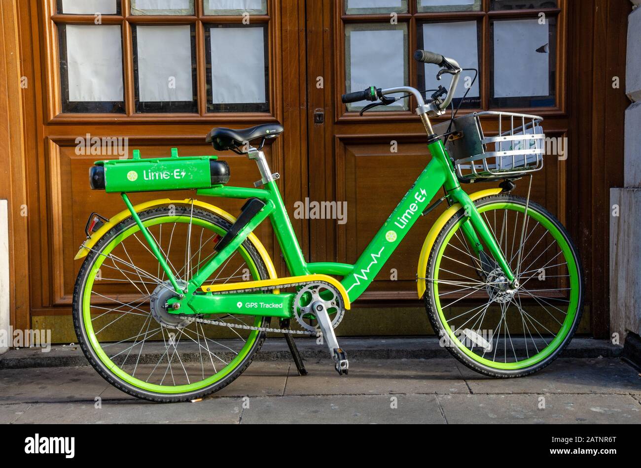 Ein Lime-Ee-Bike, das vor einer Reihe von Holztüren auf einem Straßenbelag in London, Großbritannien, geparkt wurde Stockfoto